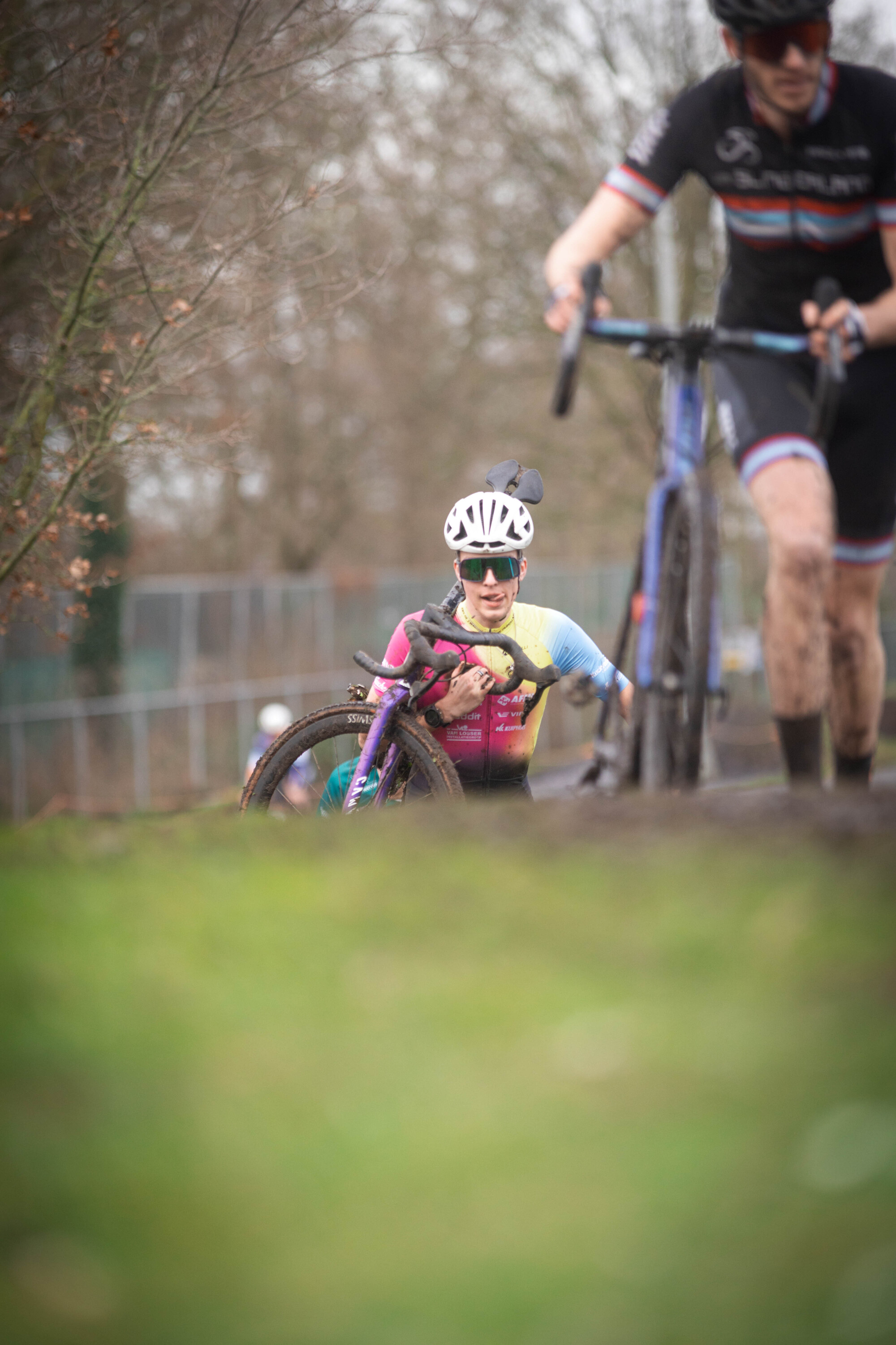 A man wearing a white helmet is on his knees behind a girl riding her bicycle.