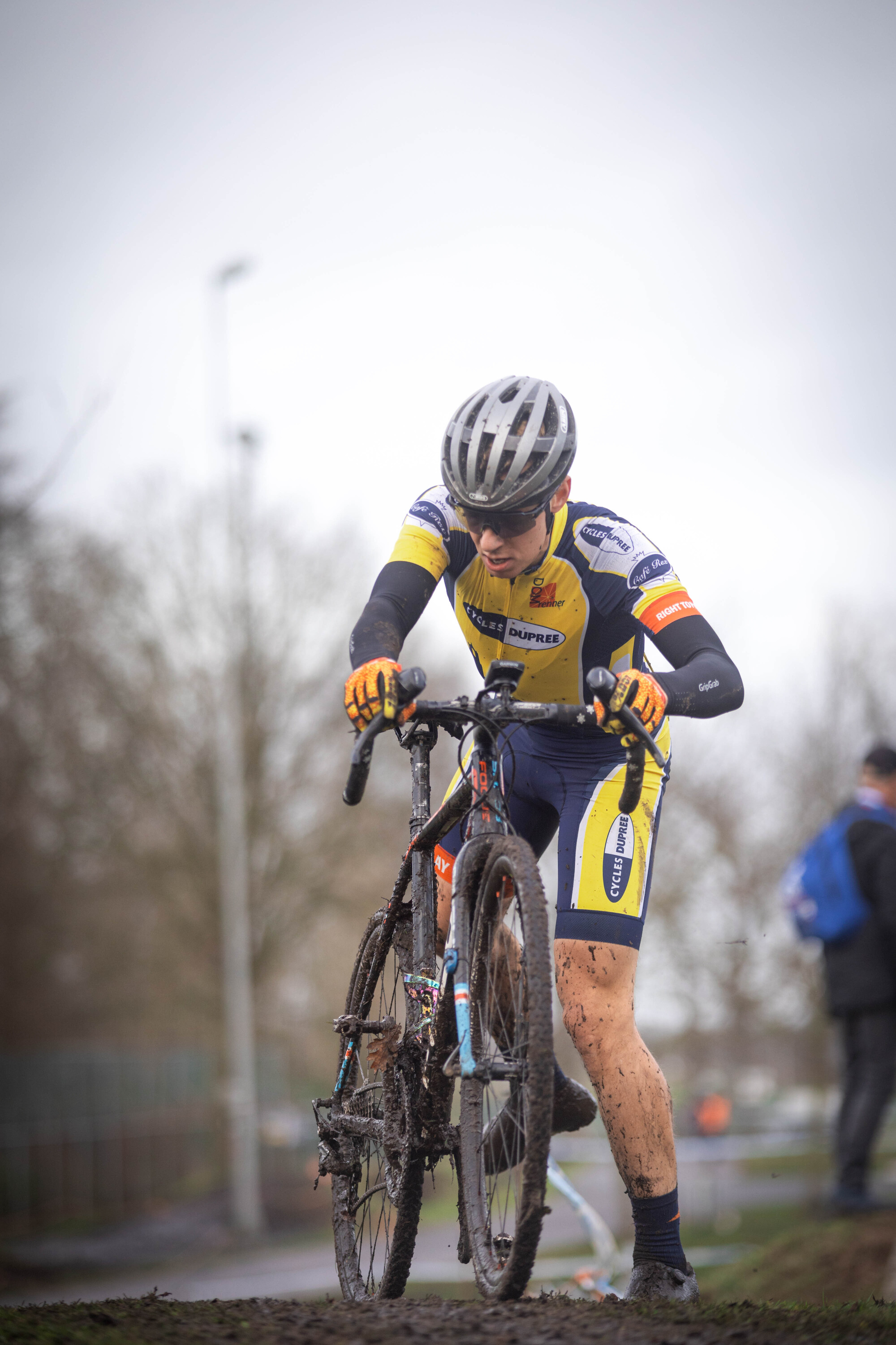 A man wearing a yellow and blue cycling suit riding his bike.