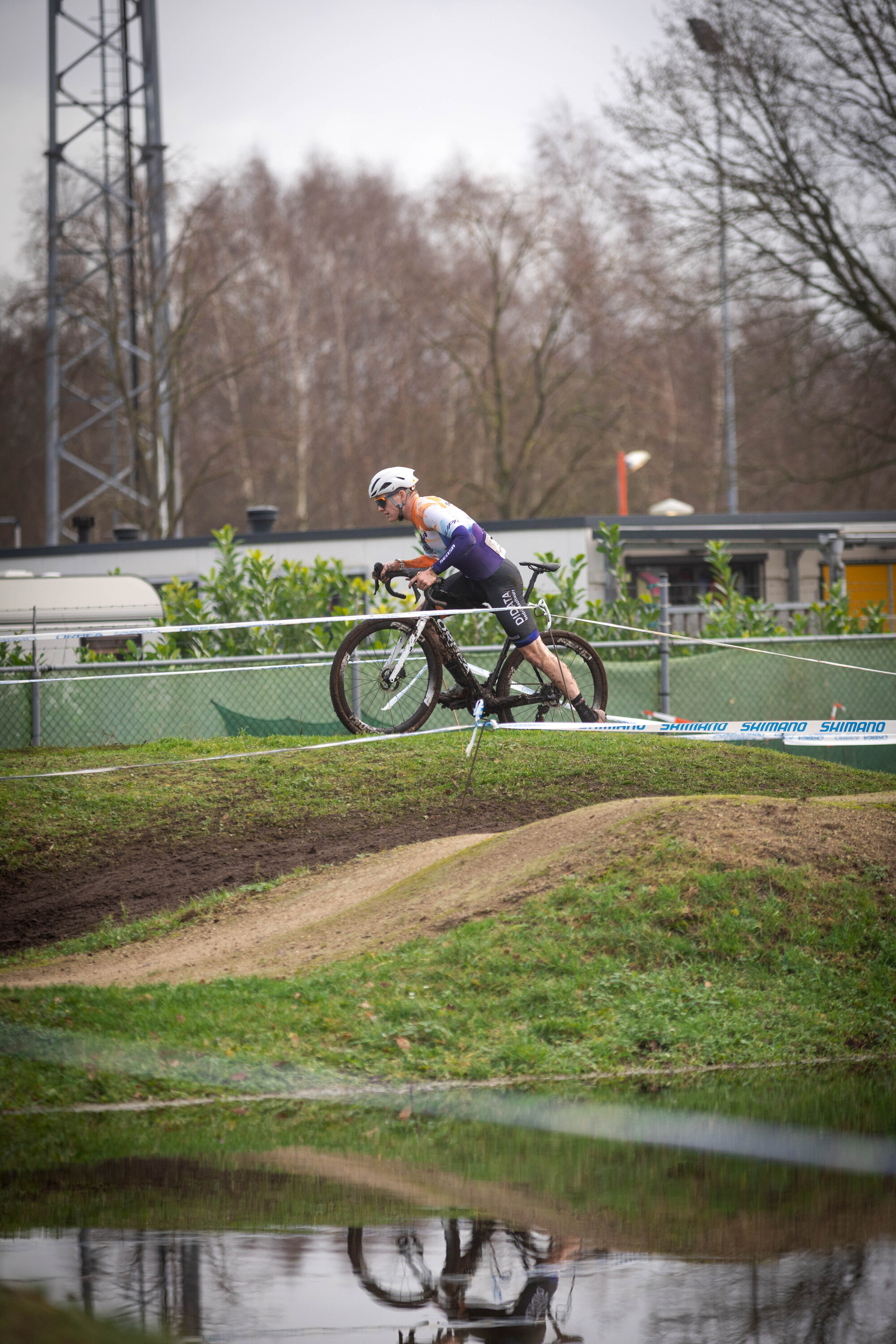 A cyclist riding a bike over a ramp with a blue banner reading Cyclocross.