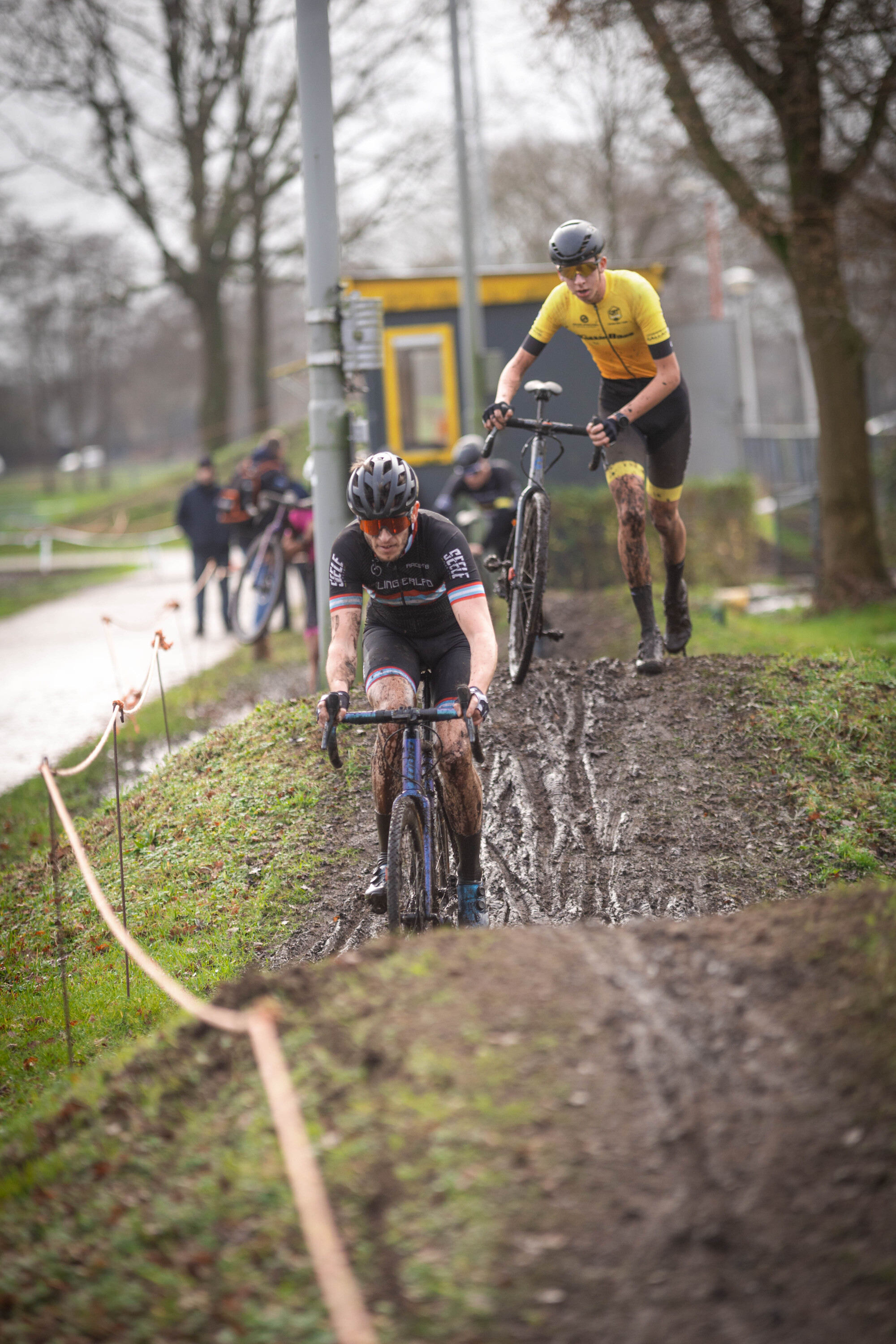 a bicyclist riding in the rain and a man standing on a bike.