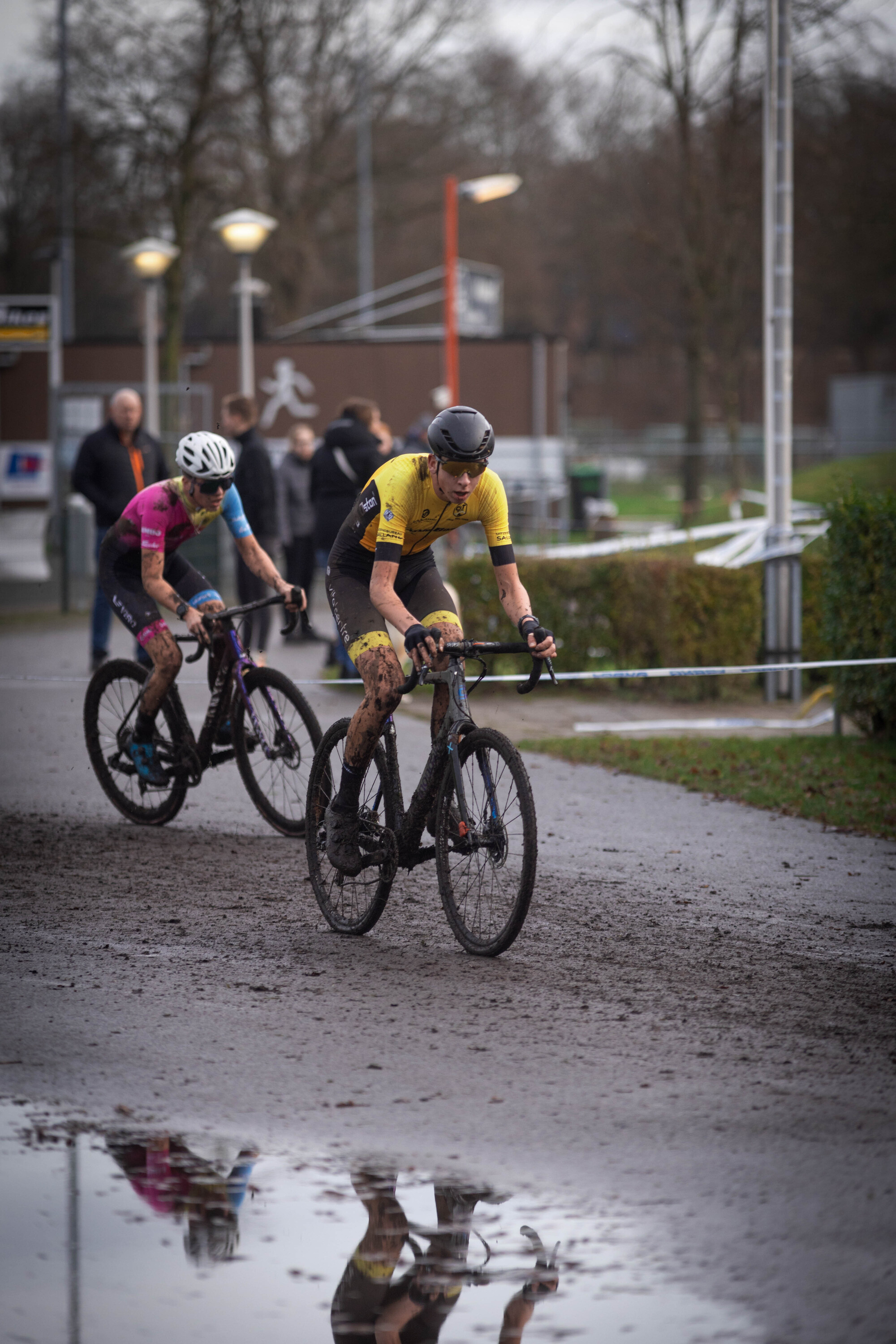 Cyclocross in Ju/Er/Bel/Amm, participants riding bikes on a dirt path.