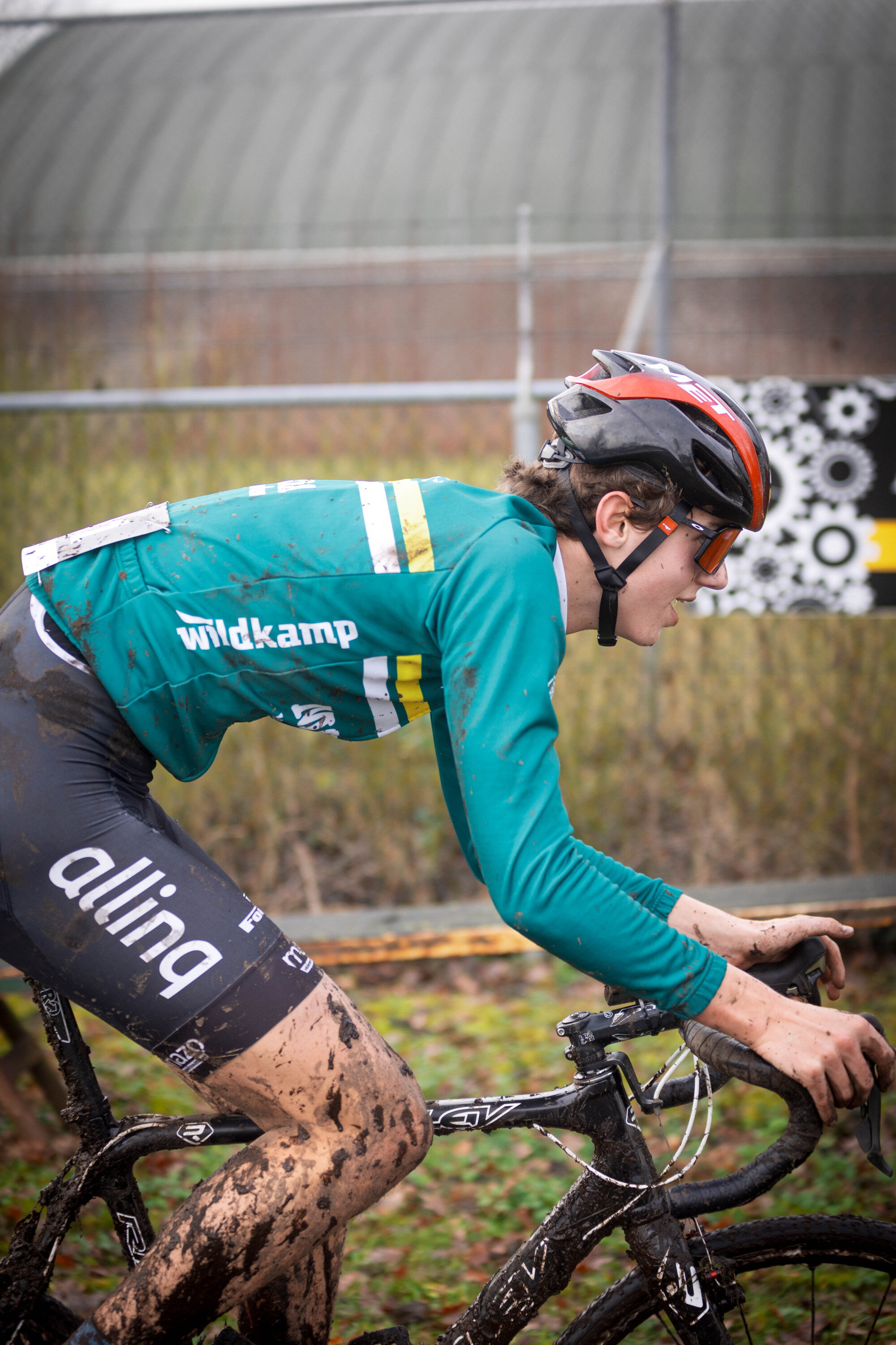 A cyclist on a black and white bike with the word "aline" on it.