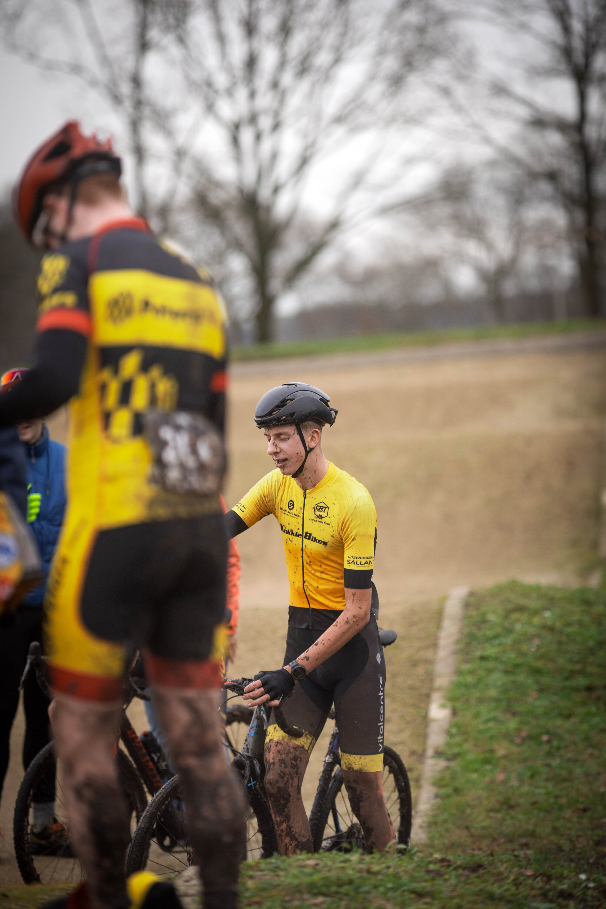 Three cyclists wearing yellow shirts with the words Ju, El and Be on them.