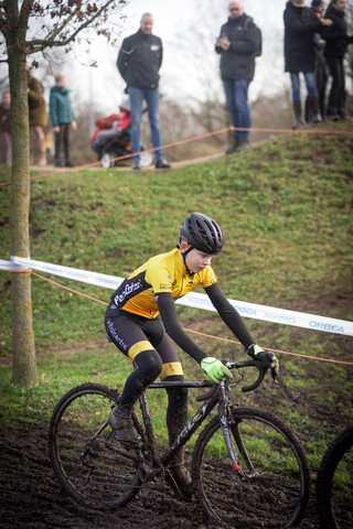 A young woman is racing a bike in the mud during the Cyclocross race.