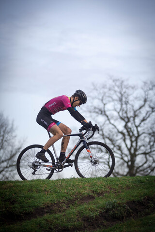 A man on a bicycle wearing a pink shirt, black helmet and shorts. The bike is red and white with the number 3 visible on it.