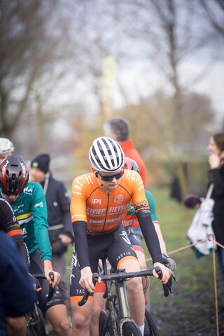 Several cyclists in a group participate in a race on a cloudy day.