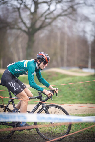 A cyclist in a green and black uniform on a bike with the word Ju/El on it.