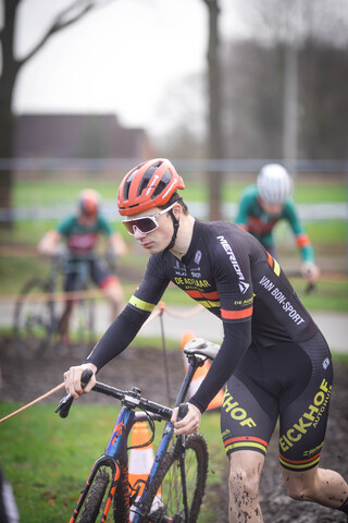 A cyclist in a red helmet is riding their bike on a field.