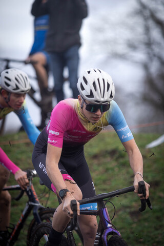 A man in a pink and blue cycling outfit is racing.