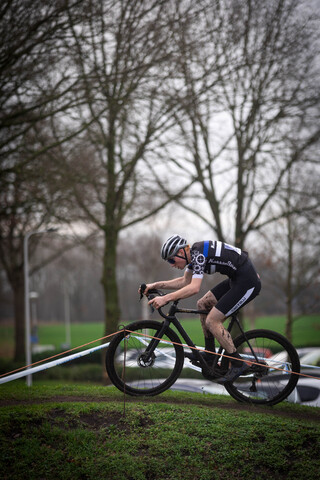 A man is riding a bike down a hill with some trees in the background.