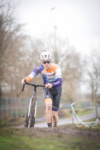 A man on a bicycle with an orange and white shirt that says GO Raalte, 2023.