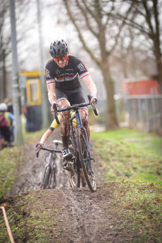 A man is riding a blue bike in a muddy track. He has the number 22 on his jersey and he's wearing a black helmet.