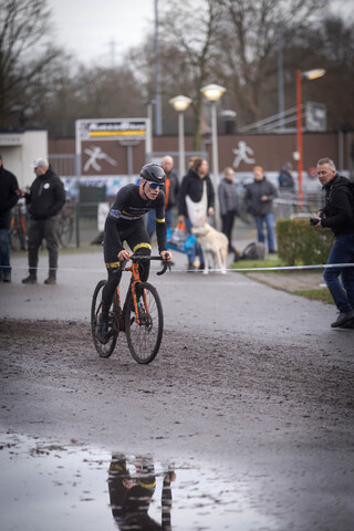 A man is riding a black and orange racing bike. He's wearing a blue helmet with the letters "GTC" on it.