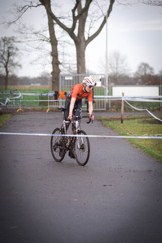 A person riding a bike down the road and wearing an orange shirt.