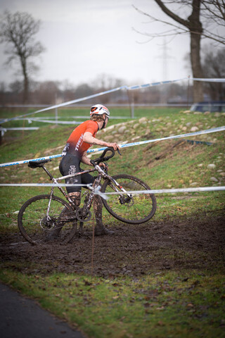 A man is riding a bike through mud on an outdoor track.