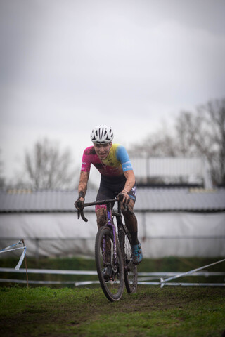 A man in a colorful shirt rides his mountain bike on the grass, preparing to take off.