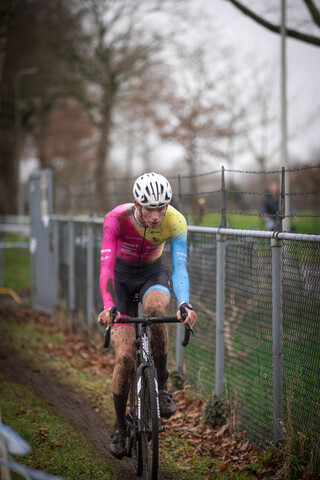 A person in a pink and blue jersey is riding a bike on a trail.