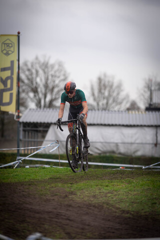 A man in a green and black shirt is riding a bike around barriers.