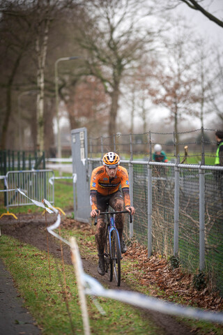 A man wearing a yellow and white helmet is riding a bike in front of a fence.