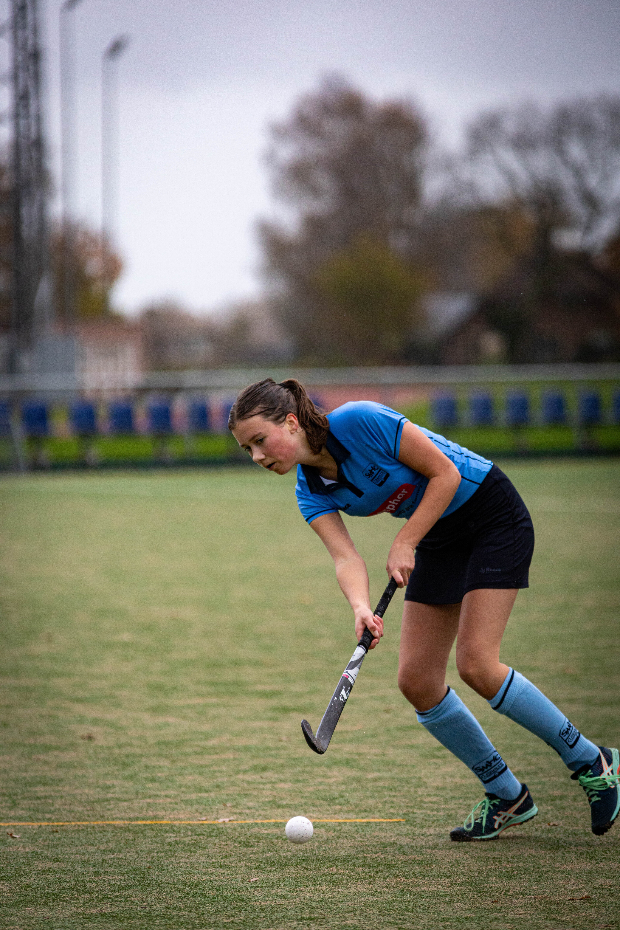 a girl wearing a blue shirt and playing with a hockey stick.