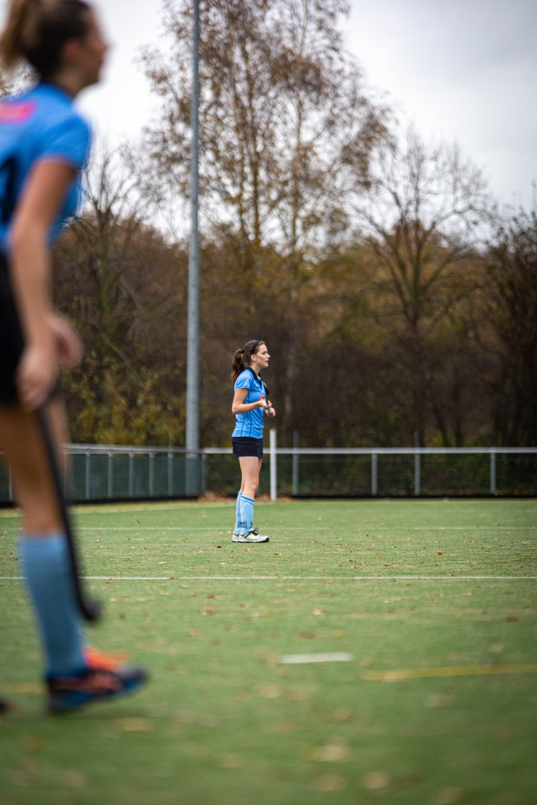 A young girl in a blue jersey and shorts is on a soccer field.