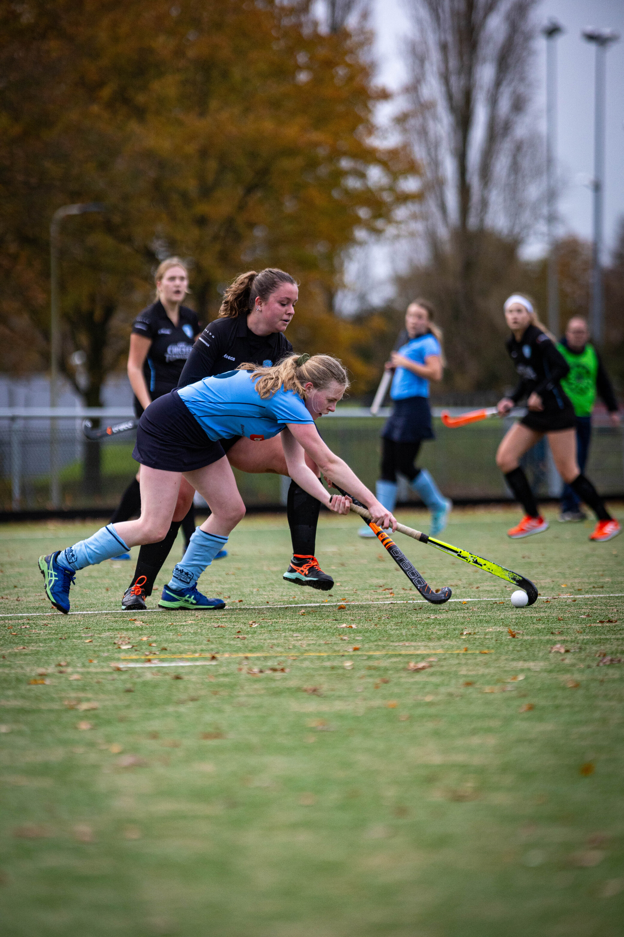 Four women playing hockey in a park on October 9th.