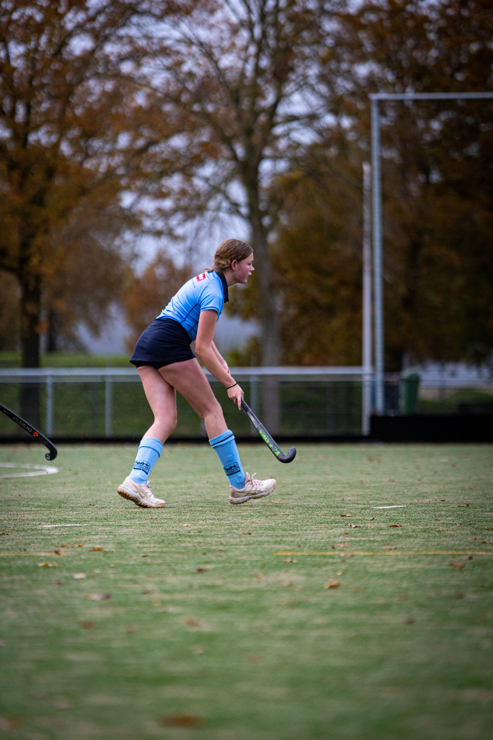 A girl in a blue hockey jersey on the field ready to play.