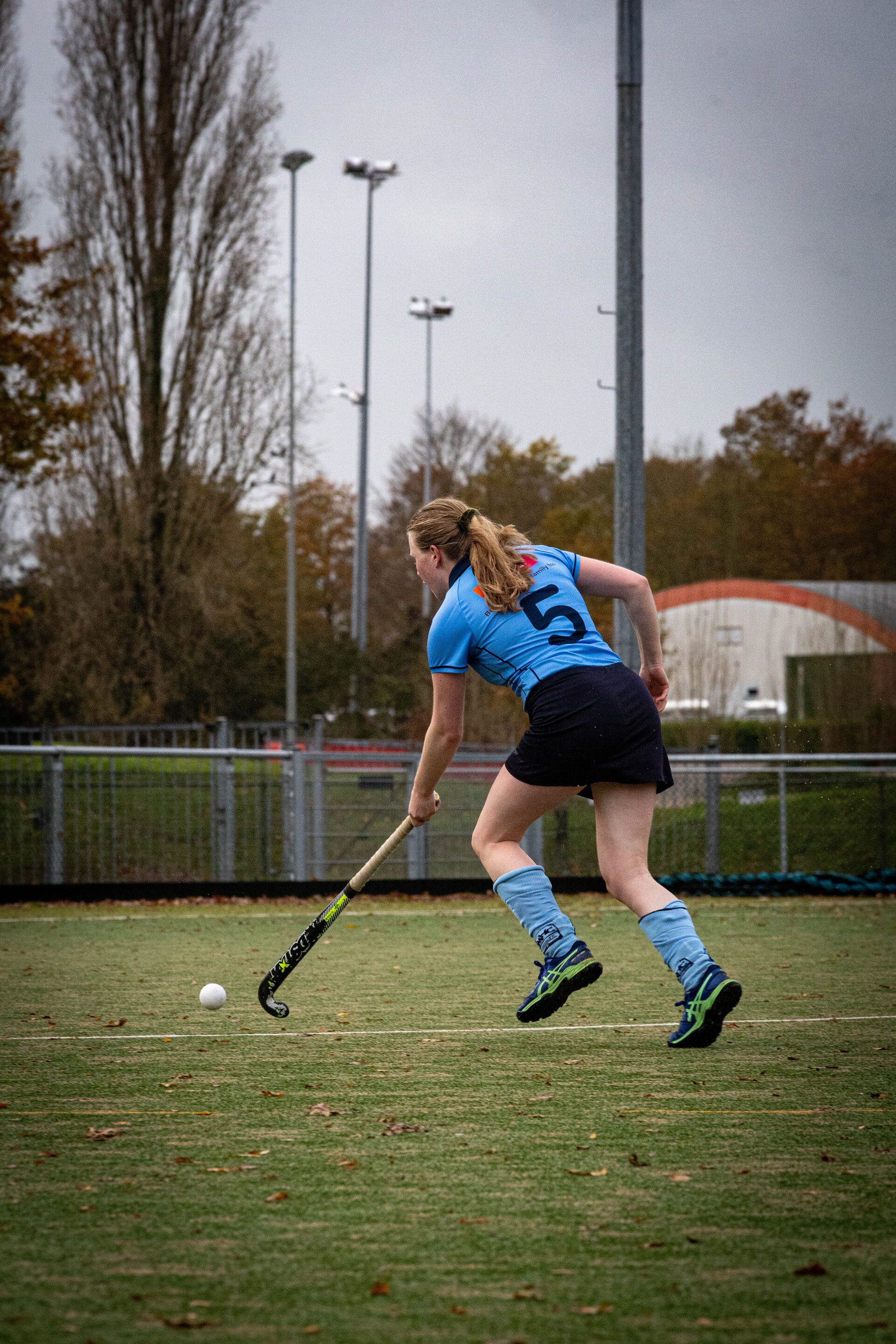 A girl in a blue jersey with the number 6 on it plays hockey.