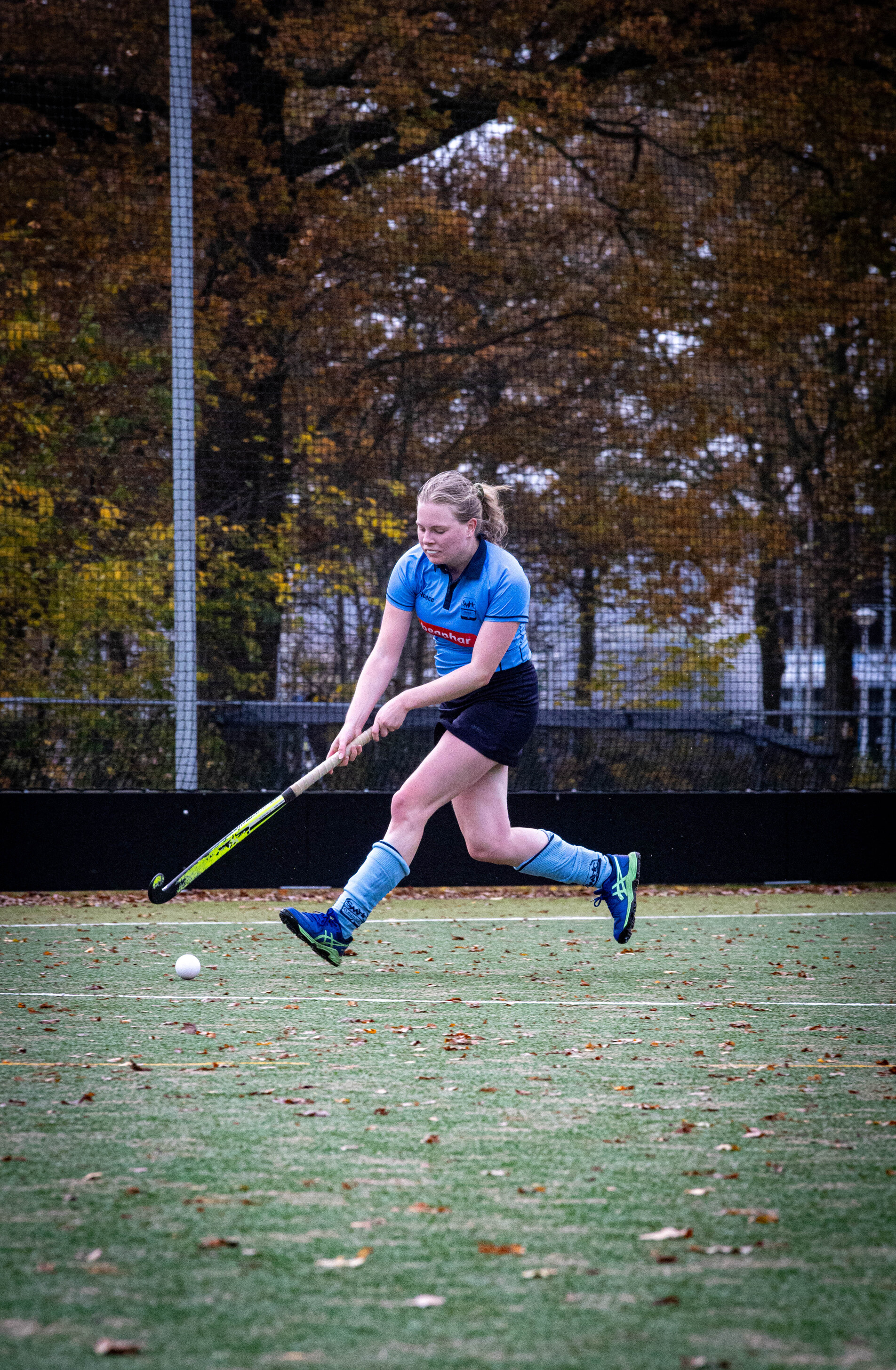 A woman wearing a blue shirt and shorts is playing hockey.