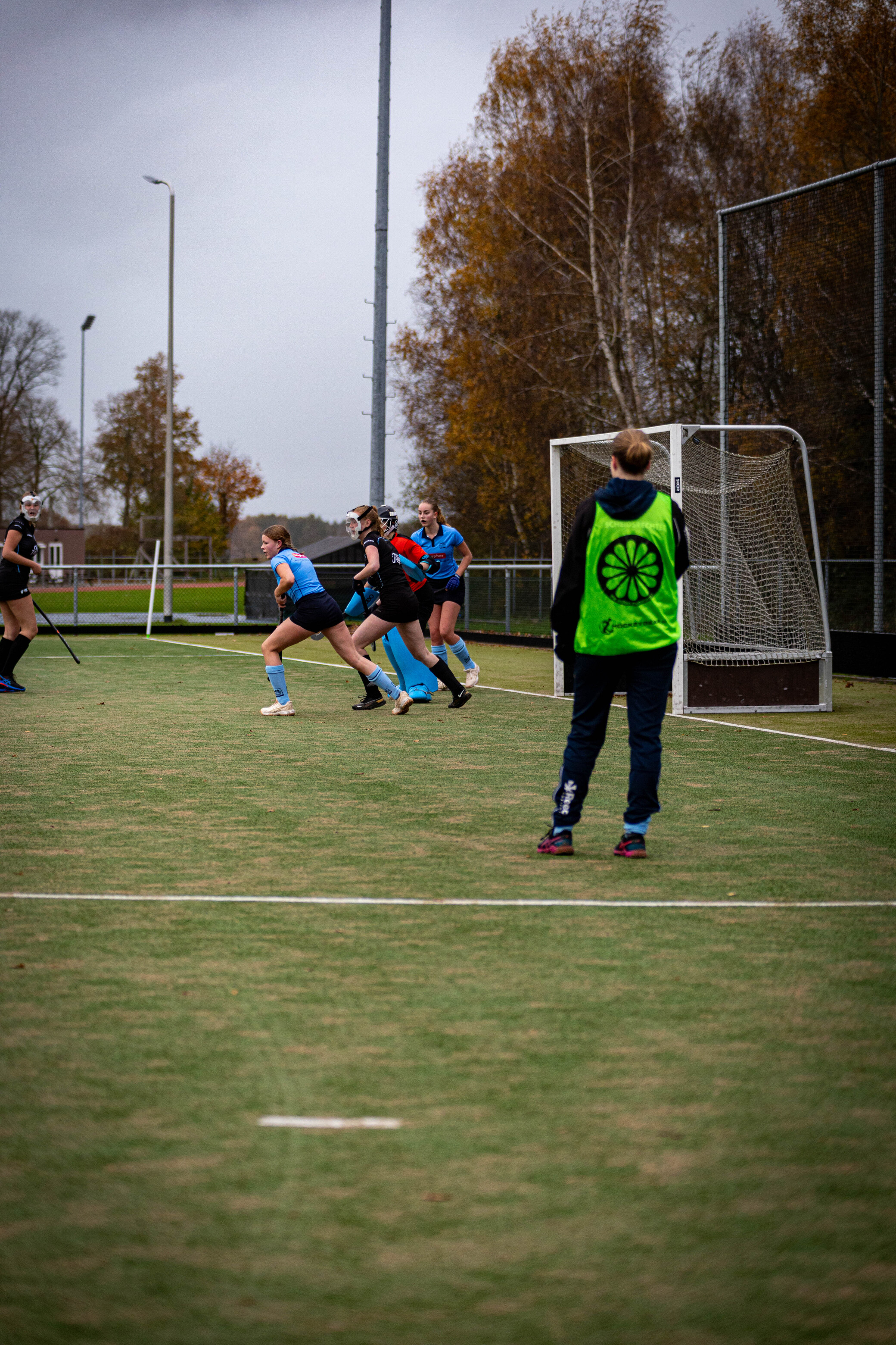 A person in a green hockey jersey is wearing a blue face mask while preparing to play.