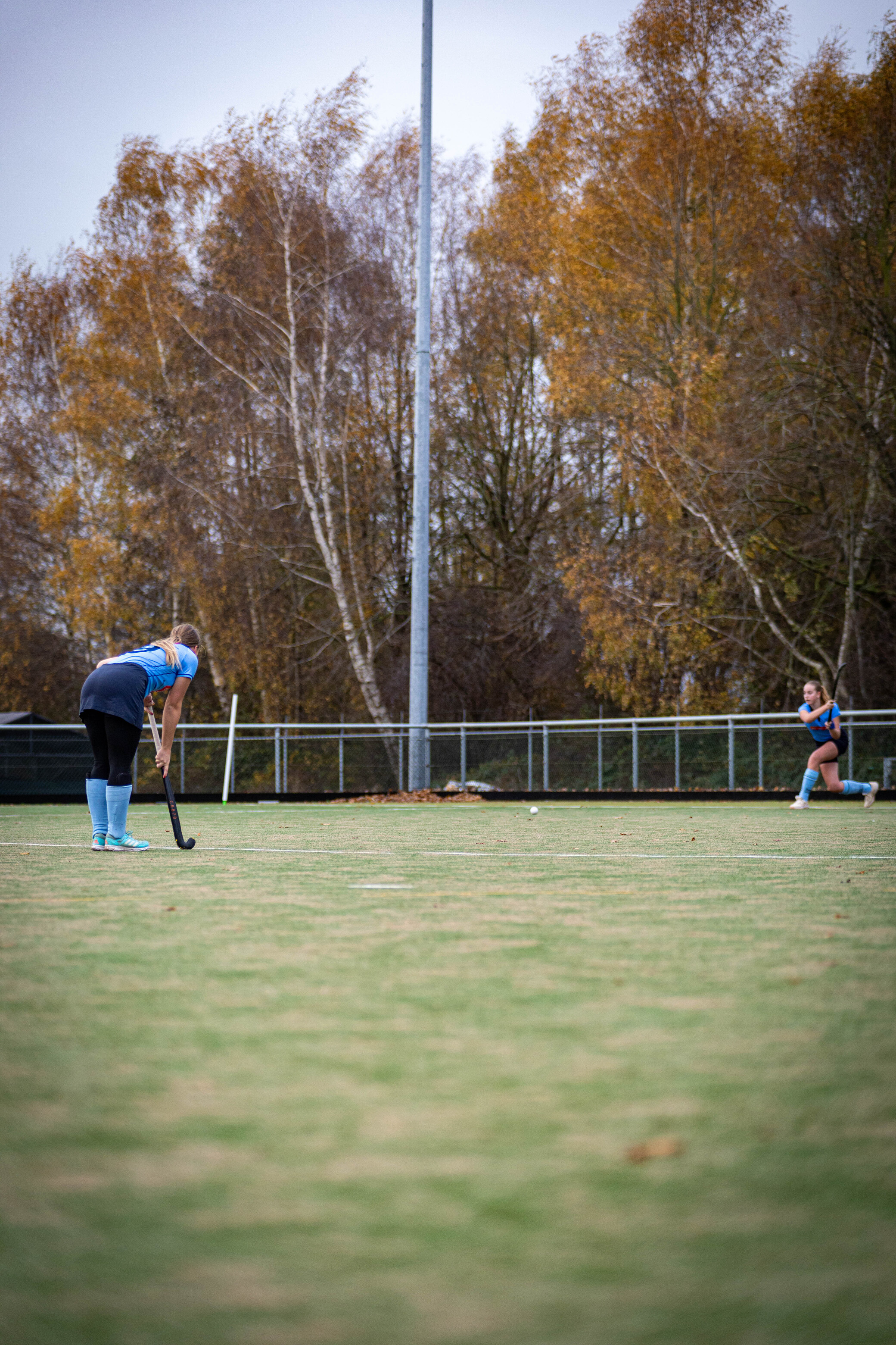 Two people are playing a game of hockey in a park.