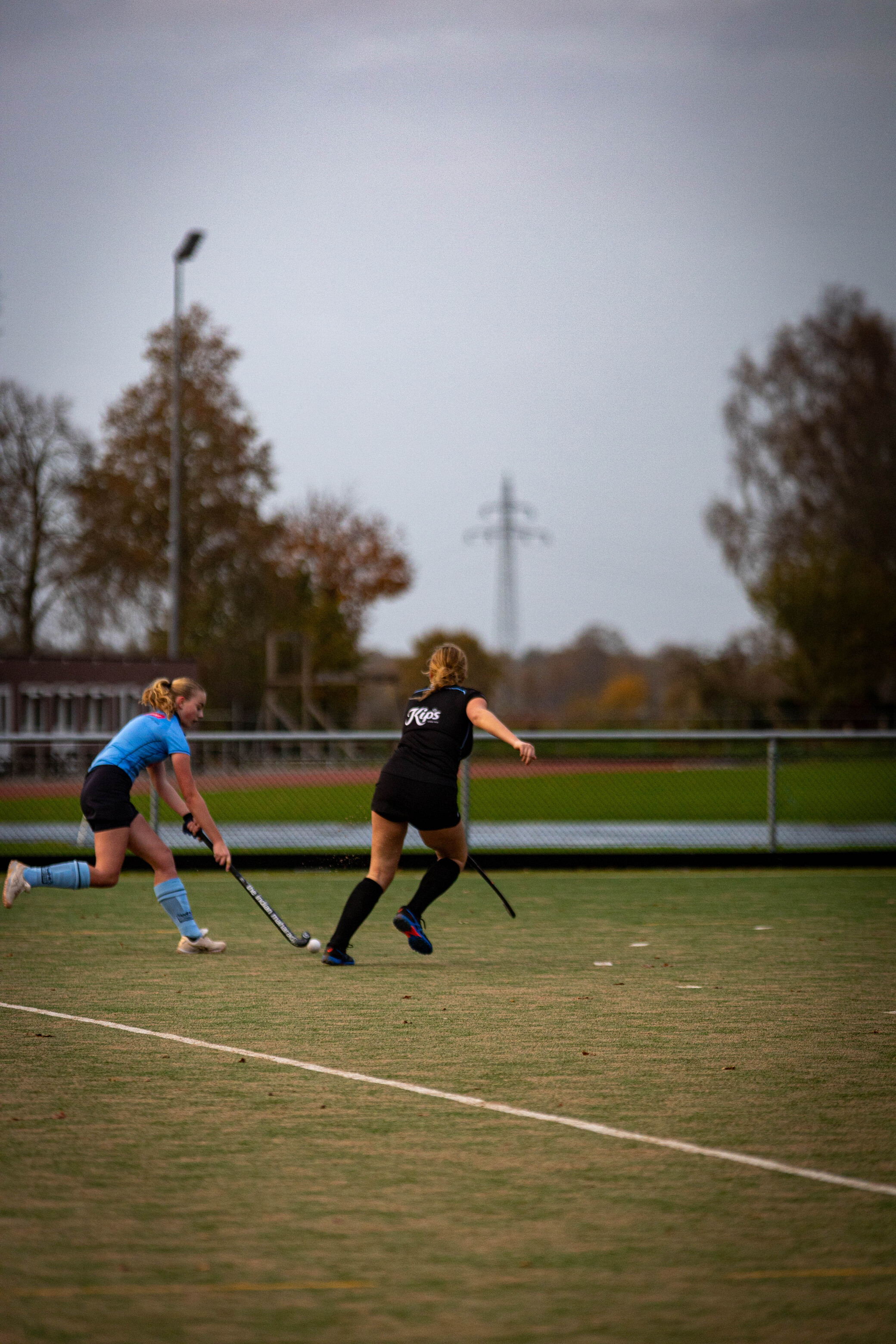 Two female hockey players on a field with one wearing the number 19.