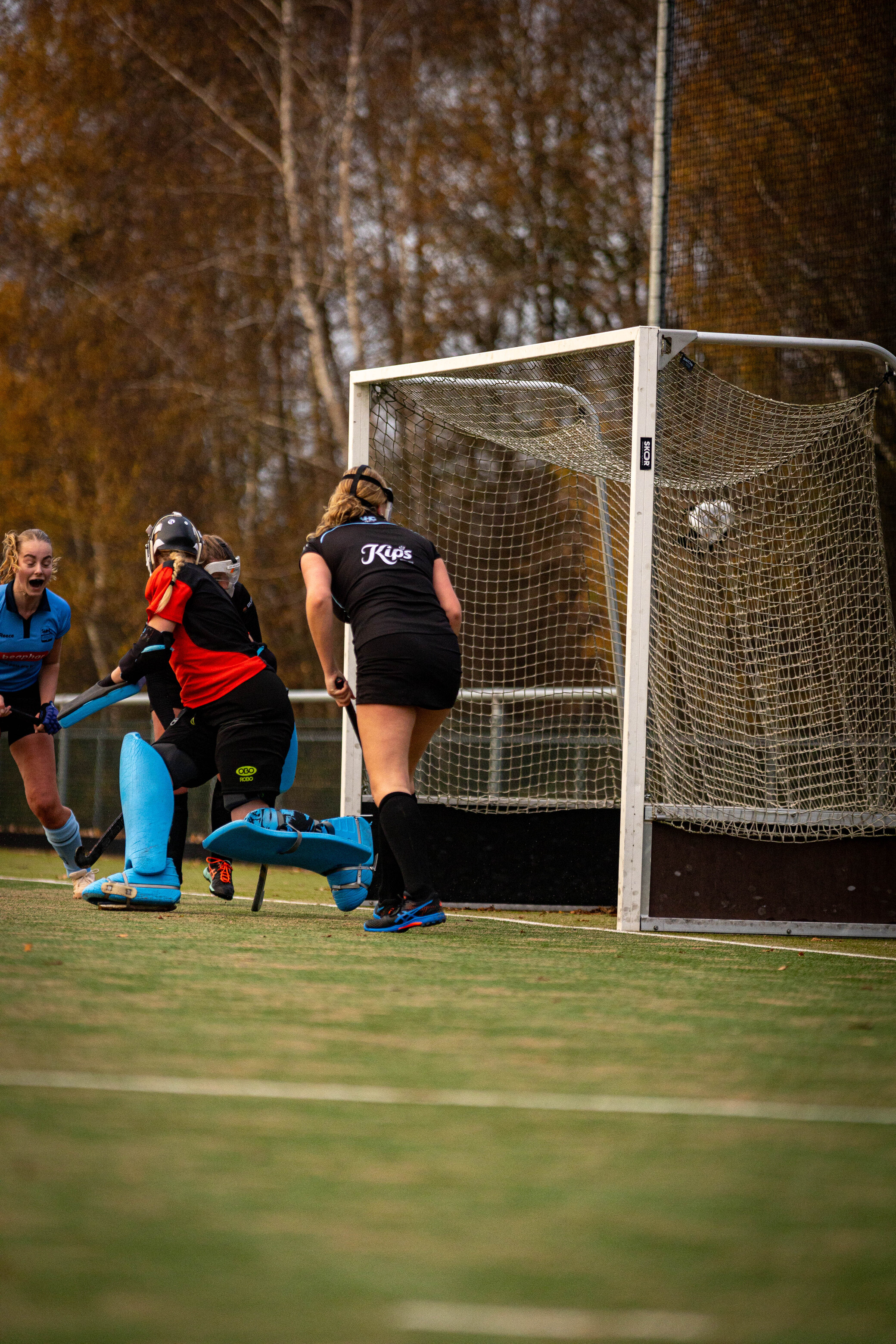 A hockey match is taking place, and the goalie is ready to stop any balls that come her way.