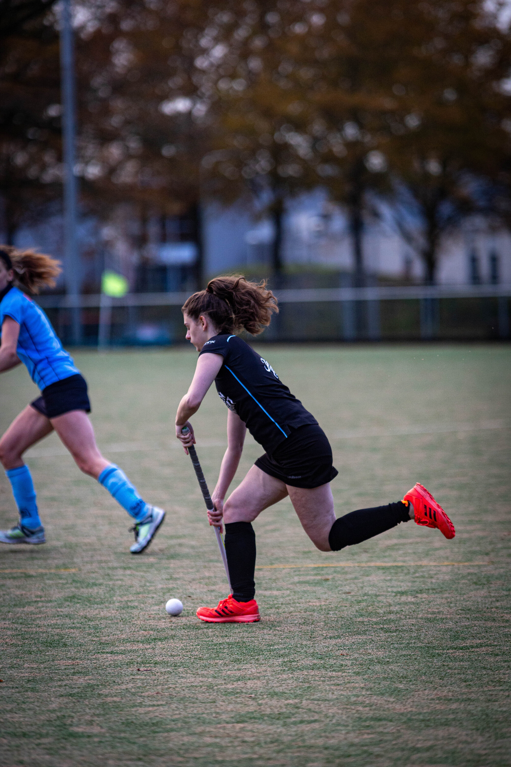 A woman wearing a black shirt with the number 19 in blue on it playing hockey.