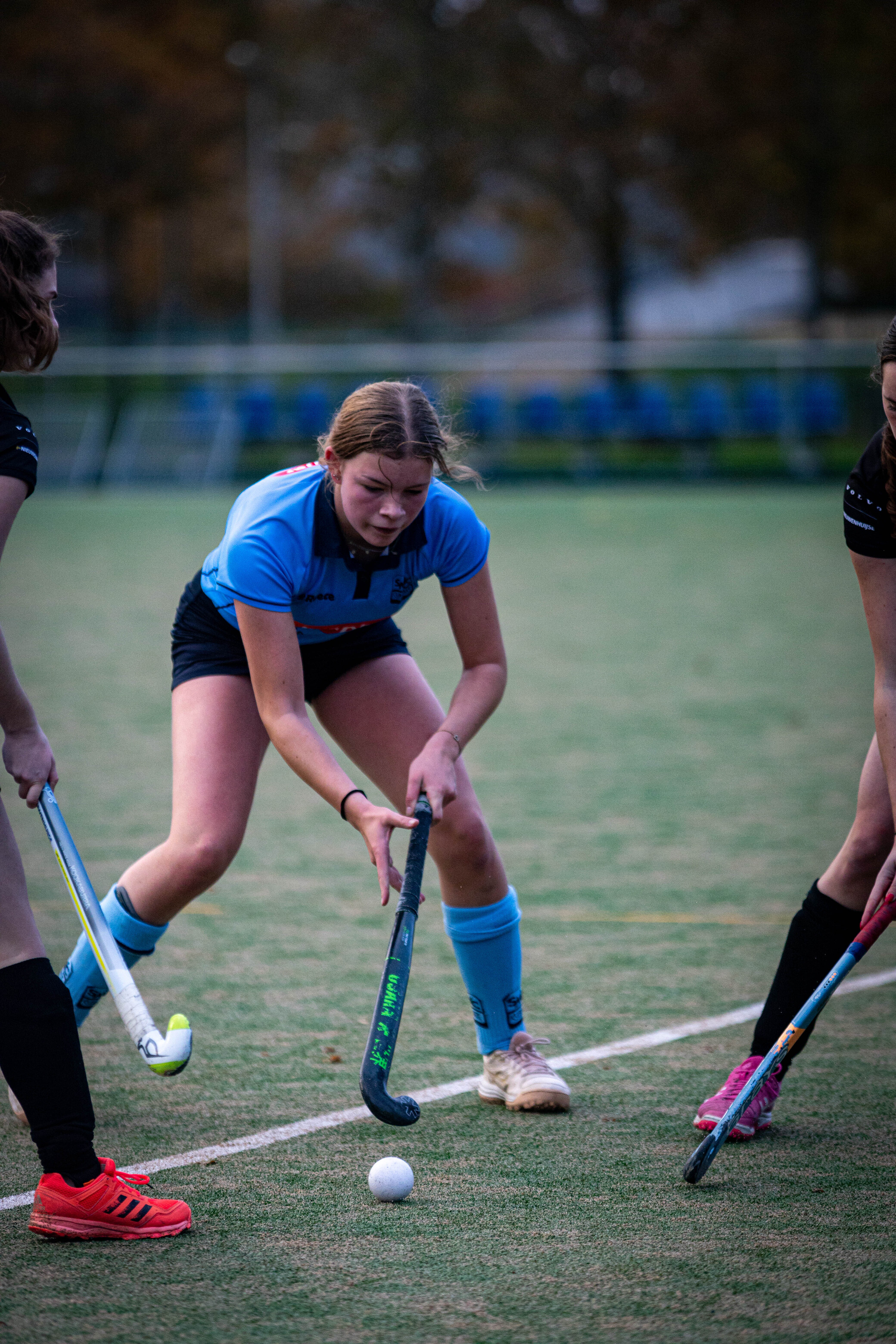 Hockey players on a field, one of them wearing a blue and black uniform with the number 19.