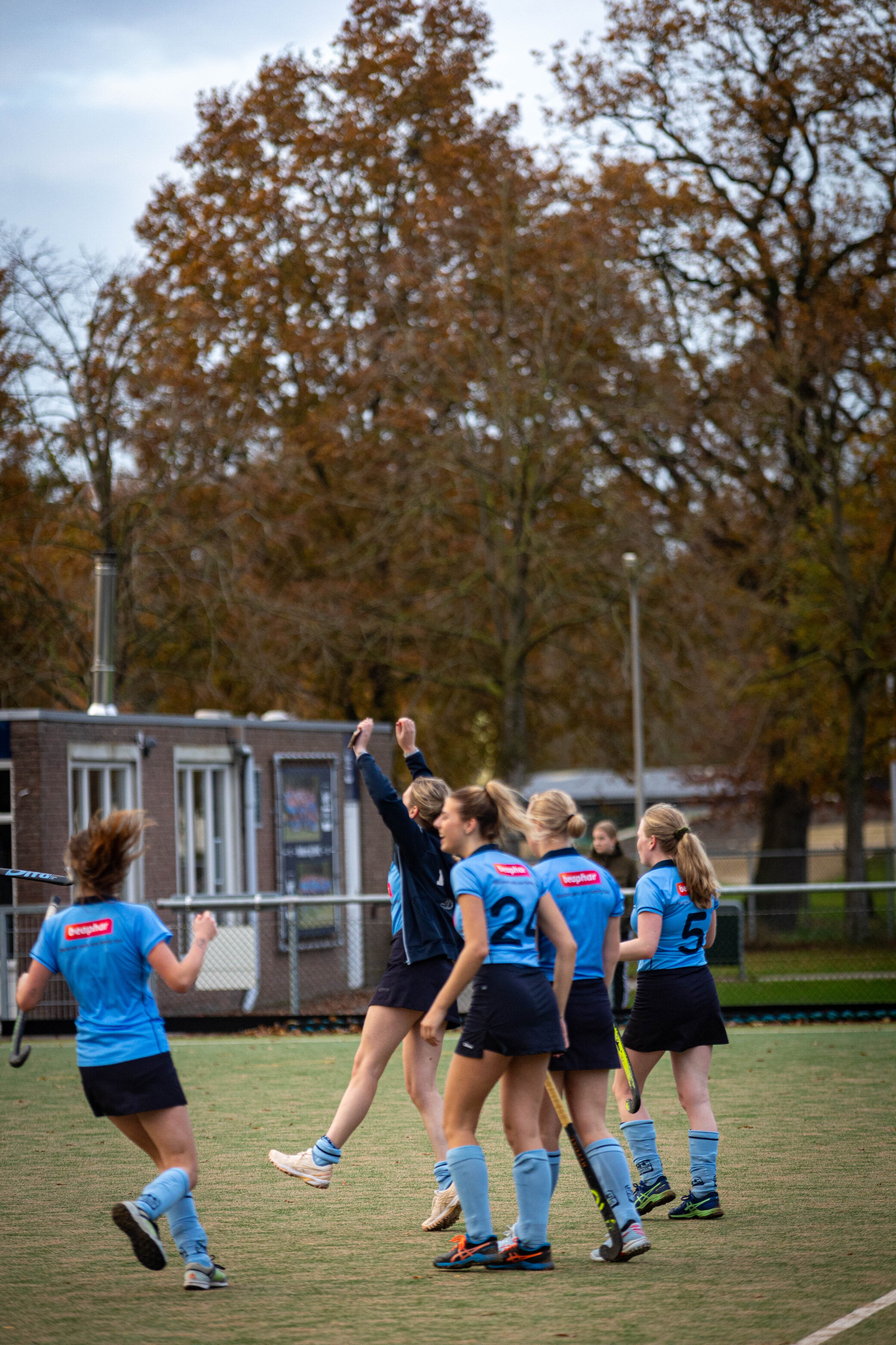 A group of women playing hockey in 2023. They are wearing matching uniforms with the number 2 on their shirts.