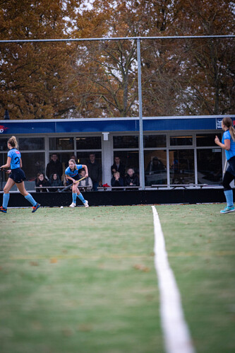 Two girls in blue hockey uniforms are playing a game on a field.