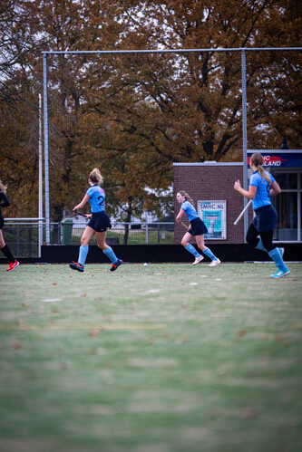 A group of girls playing hockey on a field in the fall.