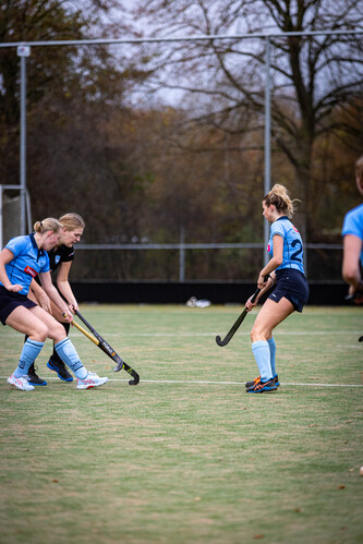 Two women playing hockey, wearing blue jerseys that say SMHC.