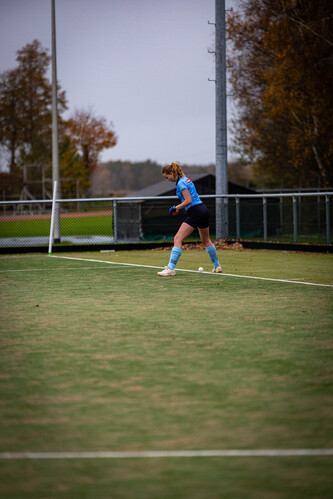 A girl in a blue hockey uniform and blue socks is skating on the grass.