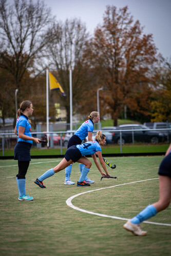 A hockey game taking place on a field with women dressed in blue uniforms.