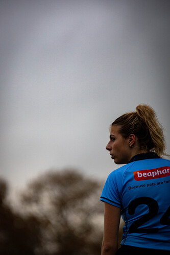 A woman wearing a blue shirt with the number 2 on it stands in front of a tree.