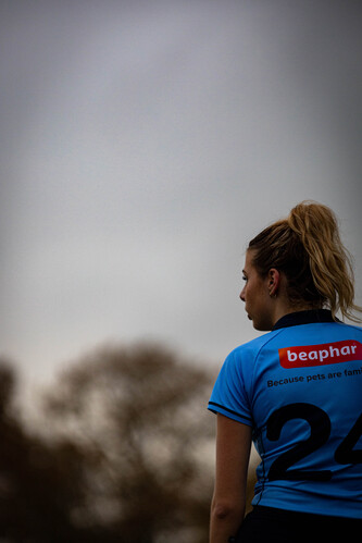 A woman wearing a blue shirt with the number 24 stands in front of a tree.