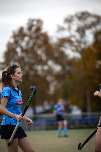 Two women playing field hockey, one is wearing a number 5 jersey.