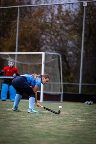 A girl wearing a blue and white hockey uniform is kneeling on the ground.