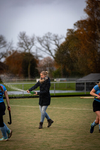 A woman playing hockey on the field during a snow storm.