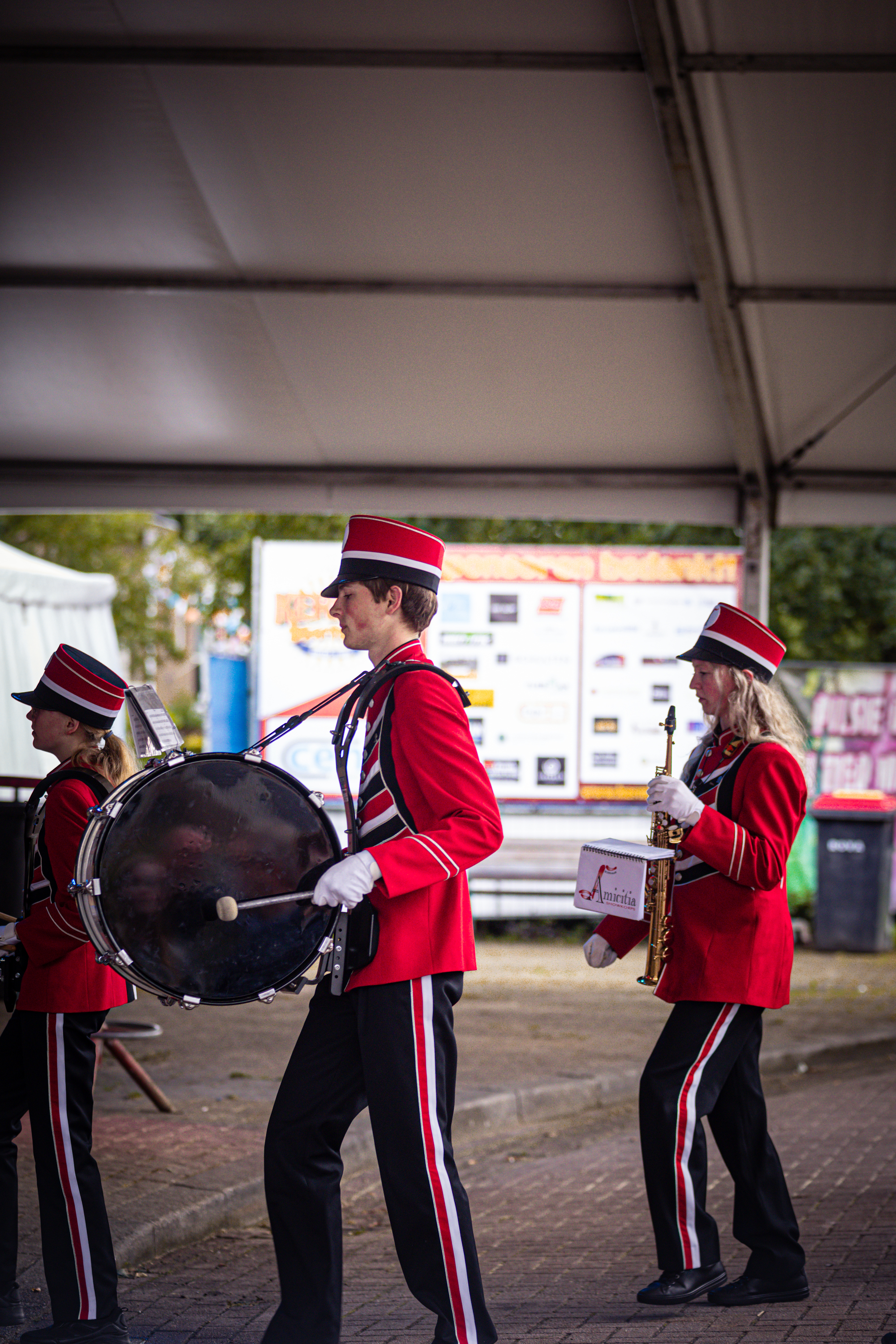 A band of three members dressed in red and black performing for a festival.