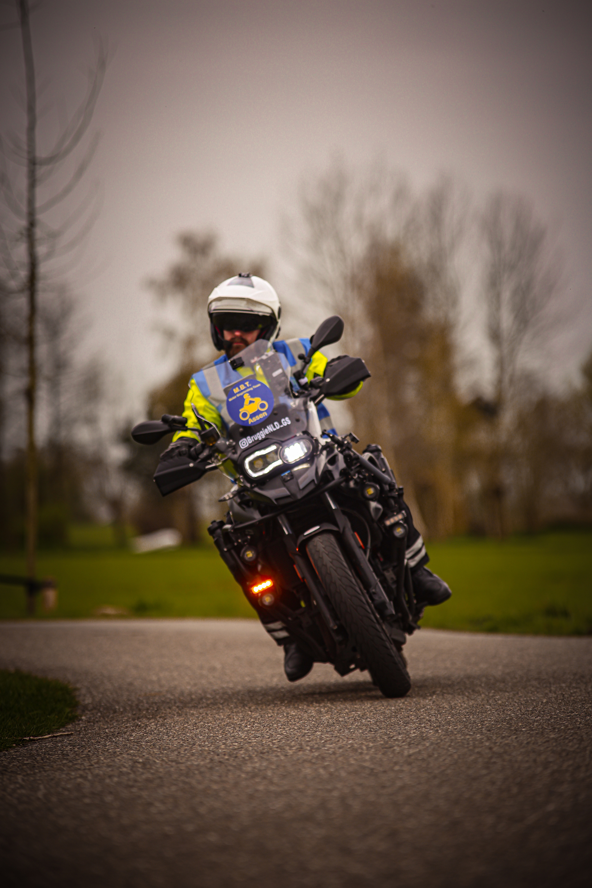 A man wearing a safety helmet rides down the road on a motorcycle.