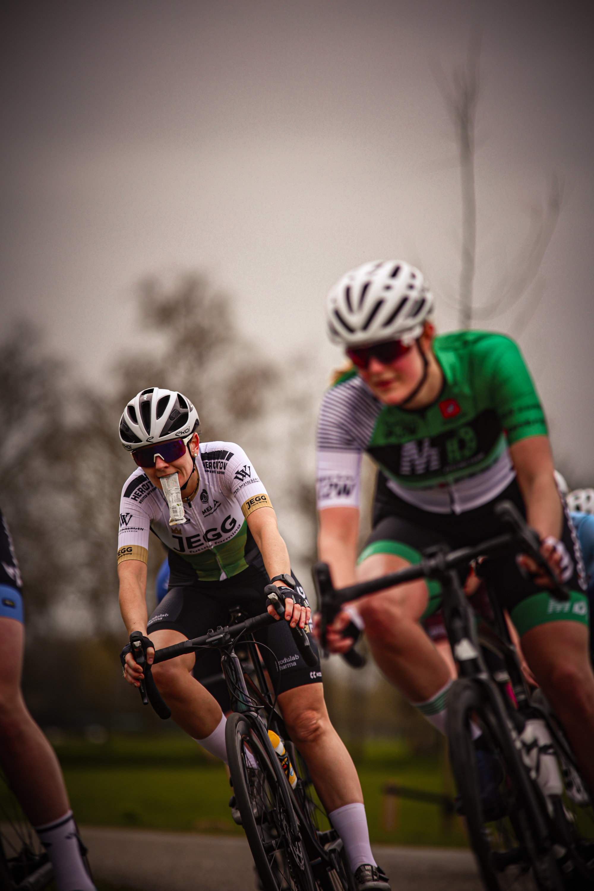 Two female cyclists in a race with one wearing a number 14.