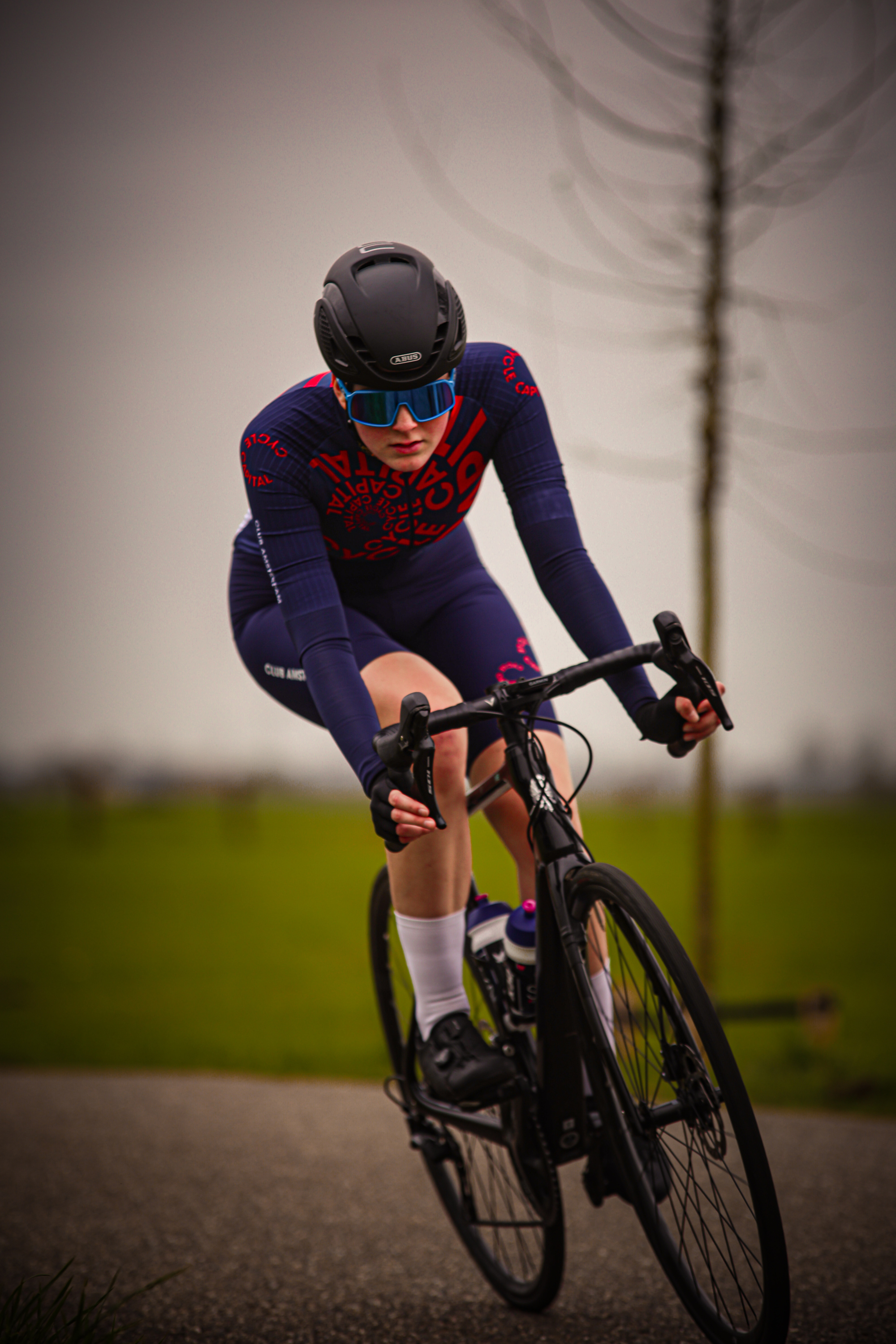 A woman in a bike race, number 24 is on her black helmet.